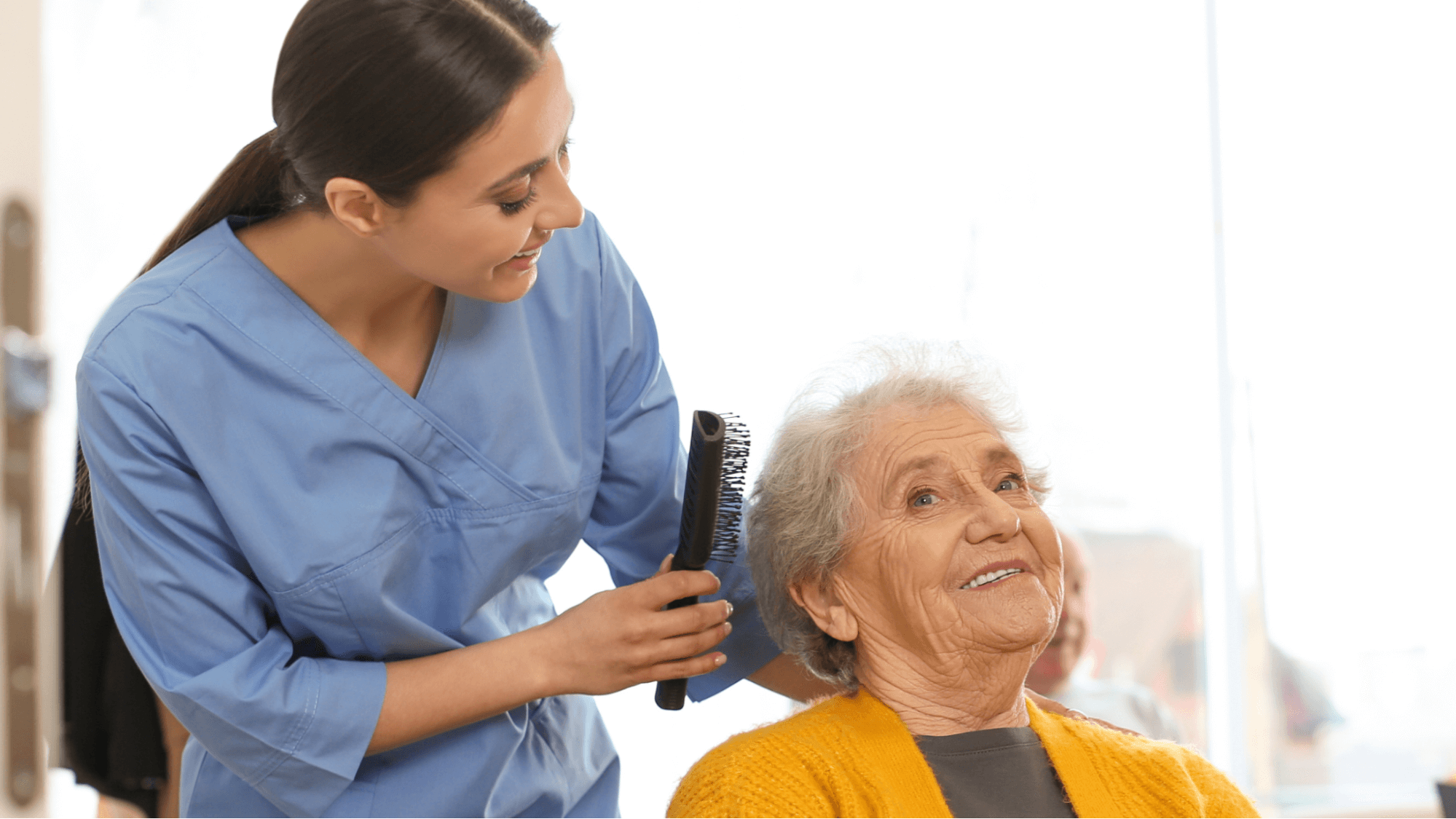 Female caregiver combing hair of senior woman sitting